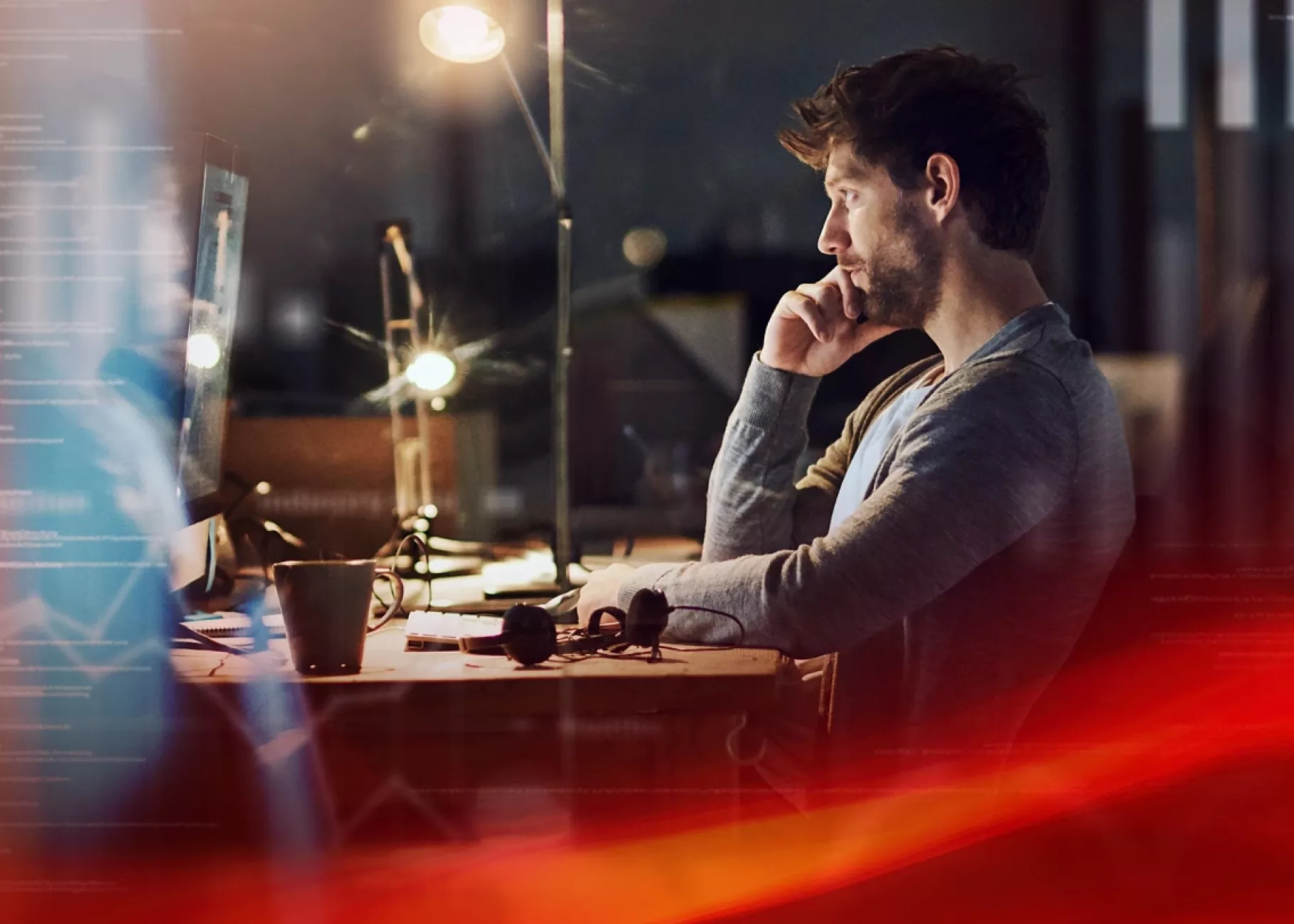 Young man sitting at desk reading computer screen with a digital abstract border overlay